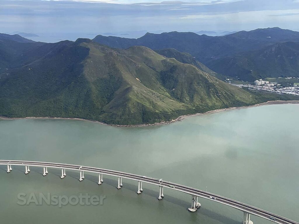 Taking off from Hong Kong international airport over the water and a bridge with mountains in the distance