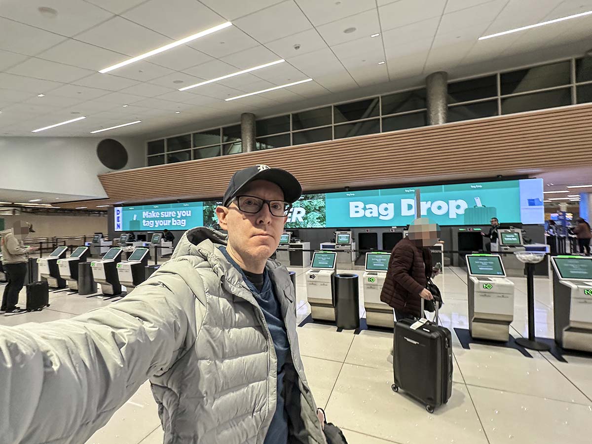 Scott Leazenby walking past the frontier Airlines check-in area and baggage drop at DEN