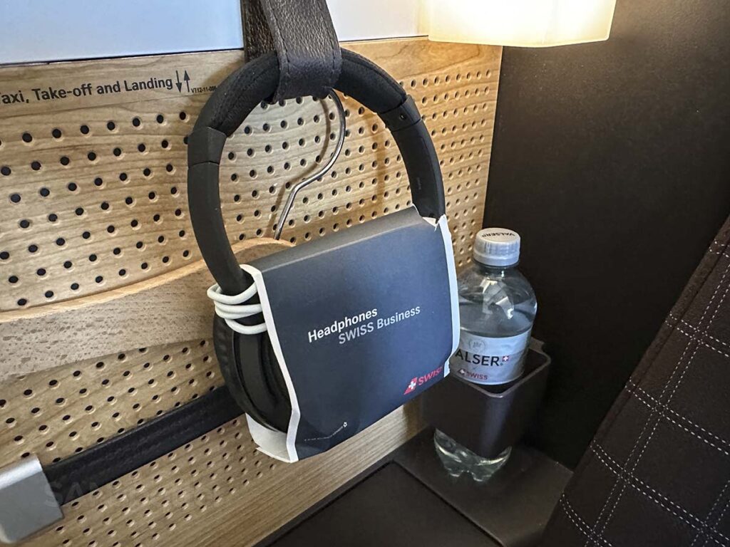 Swiss 777-300ER business class complementary bottled water, noise canceling headphones, and coat hanger