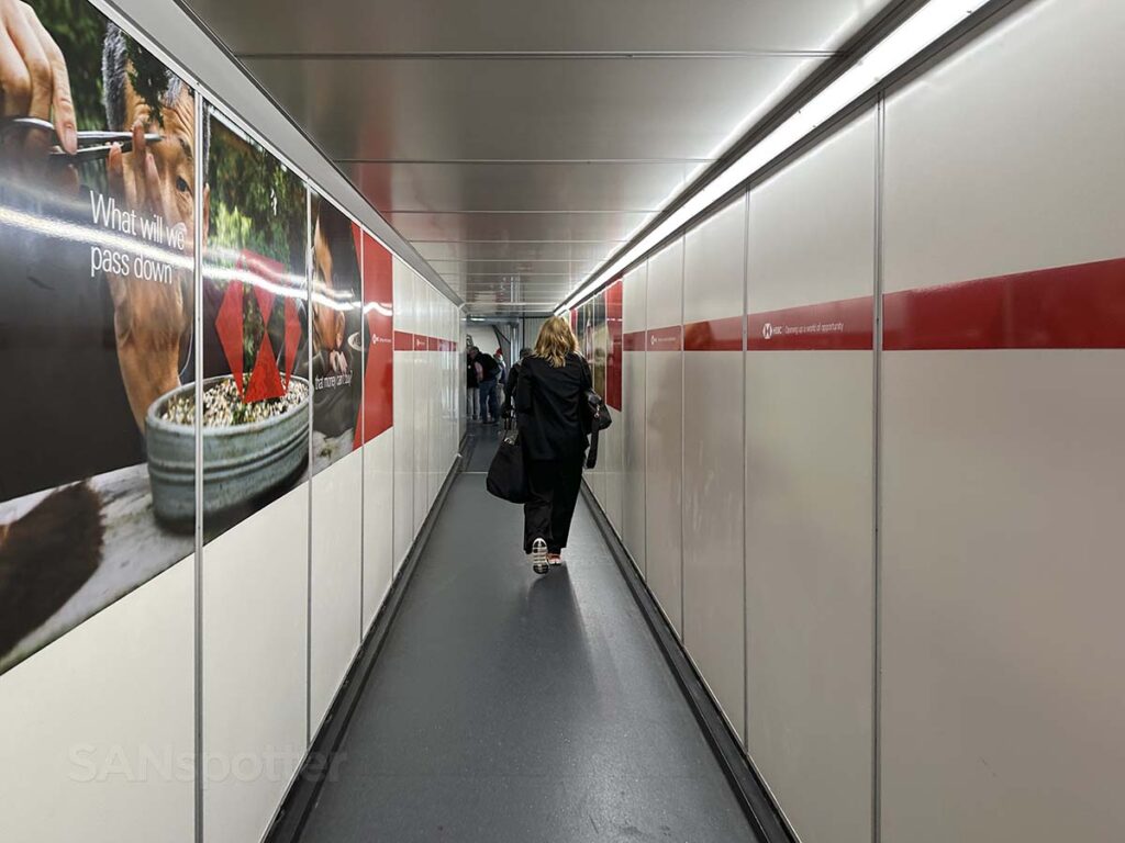 Passengers walking down gate A24 jet bridge terminal 2 Heathrow Airport