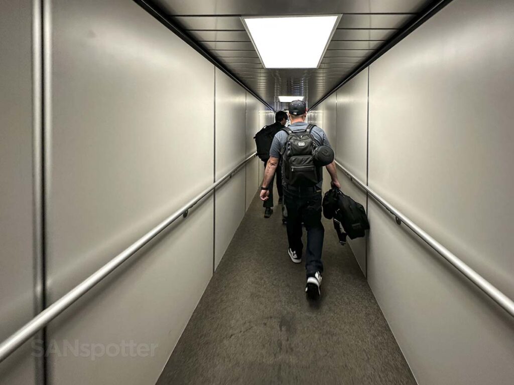 Passengers walking down the jet bridge to board the plane gate 133 LAX