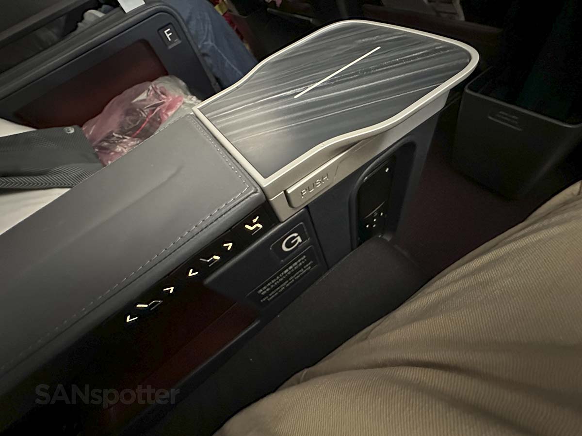 JAL A350-1000 premium economy center armrest with seat controls, drink tray, and remote control for video entertainment
