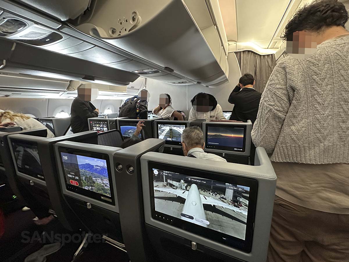 Passengers standing up and retrieving their luggage from the overhead bins while waiting to deplane in AL A350-1000 premium economy