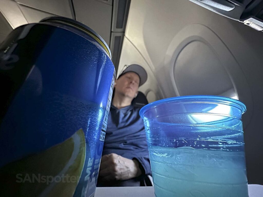 Napping in United A321neo Economy Plus with drinks on my tray table