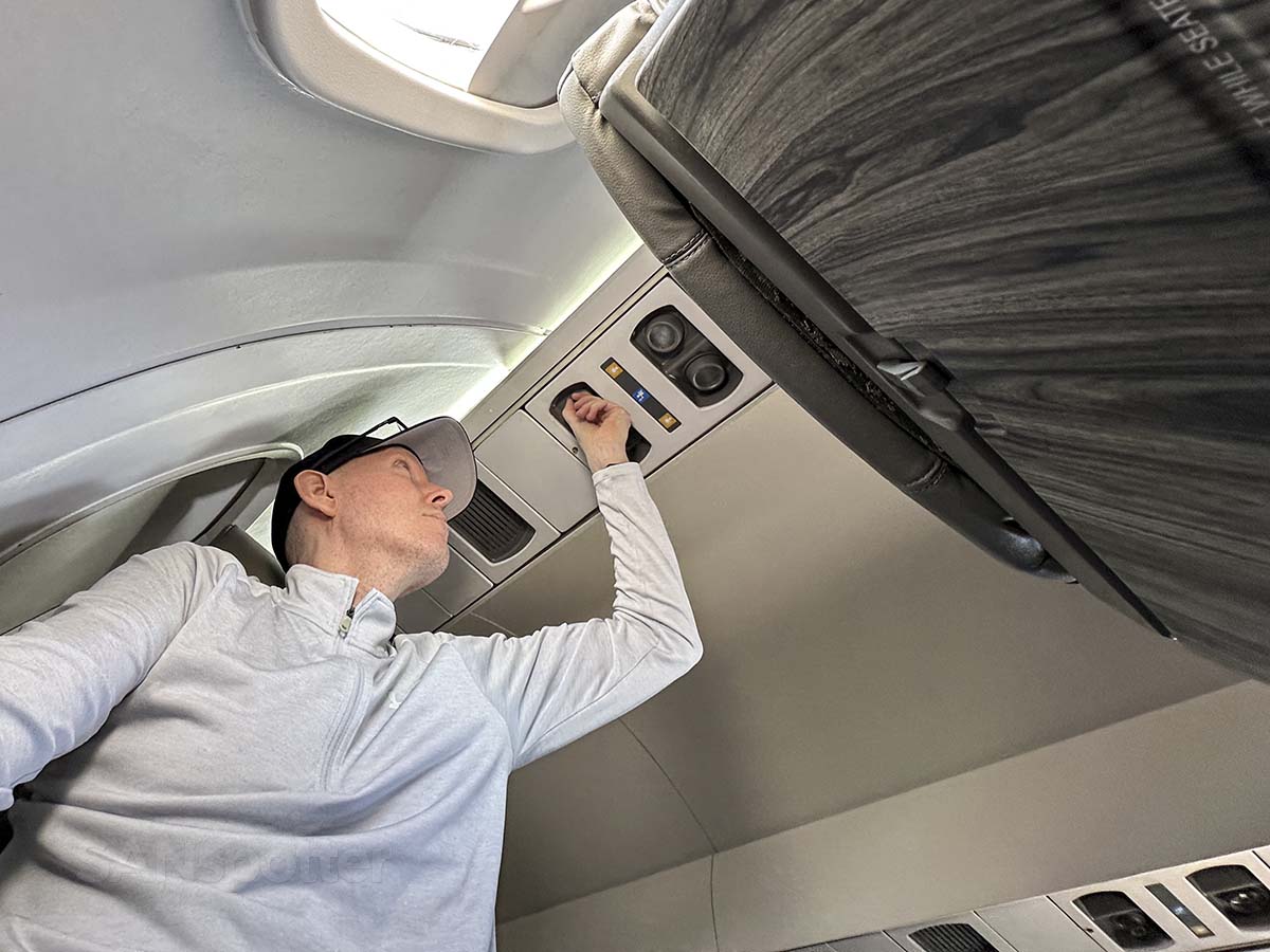 Scott Leazenby adjusting the overhead air vent in seat 5C on a JSX E145