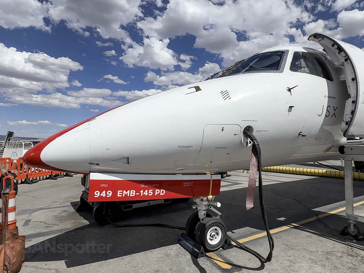 The nose and front landing gear of a JSX Embraer 145 parked on the ramp at LAS