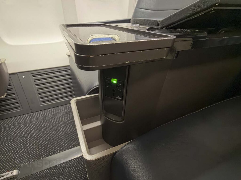 Power outlets and storage compartments under the armrest in United Airlines 757-300 first class