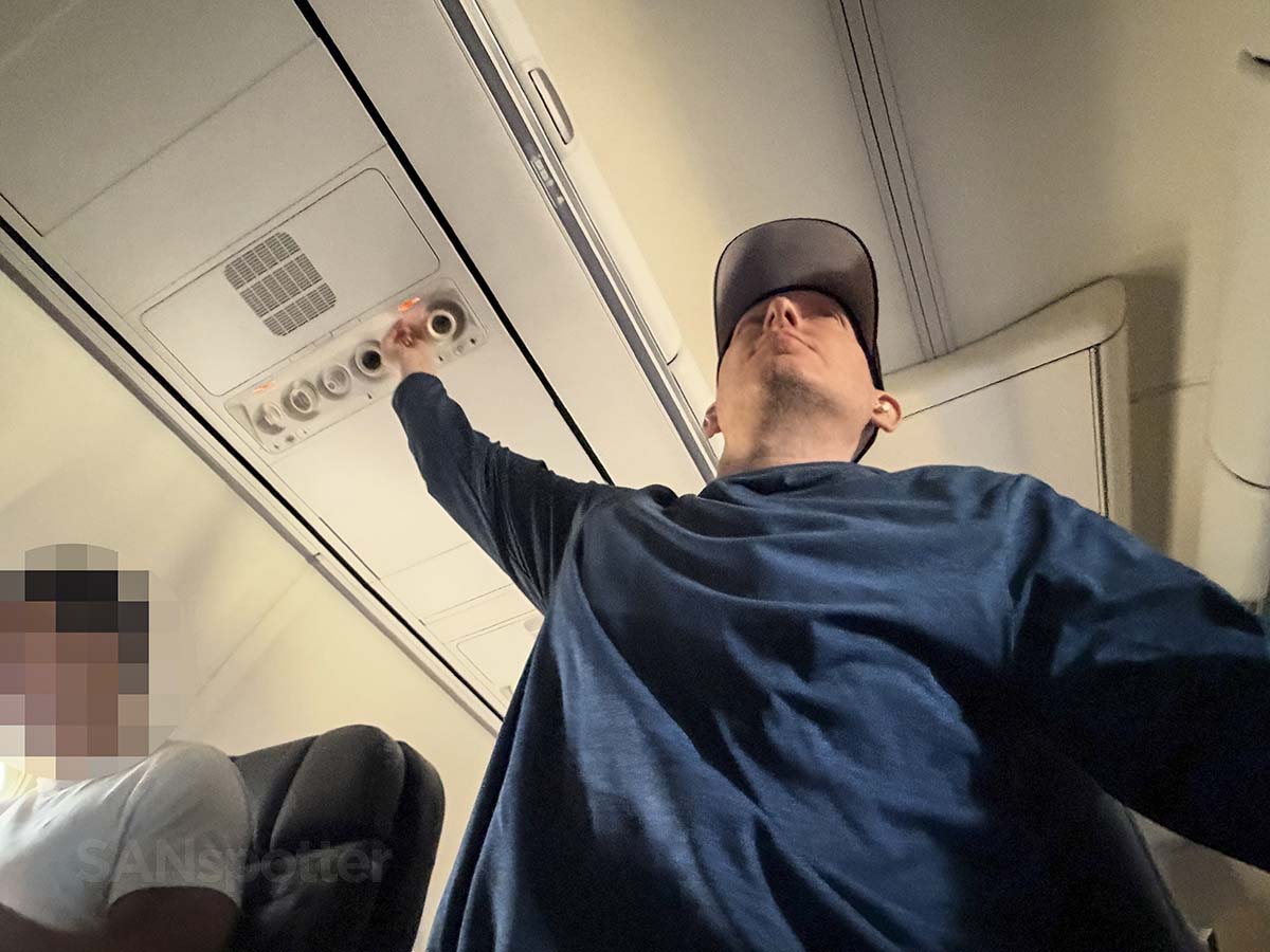 Scott Leazenby adjusting the overhead air vent in United Airlines 757-300 first class