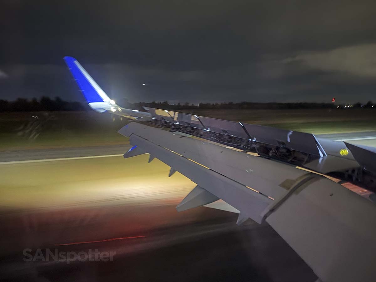 Looking out the window at the wing and winglet of a United Airlines A321XLR while landing on runway 01L at IAD in the dark